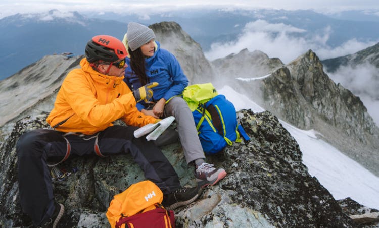 Dos personas sentadas en una montaña nevada