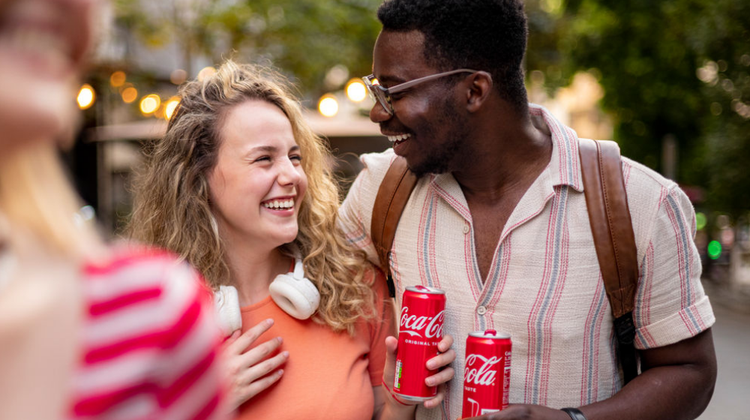 Eine Frau und ein Mann, die eine Dose Coca-Cola in der Hand halten