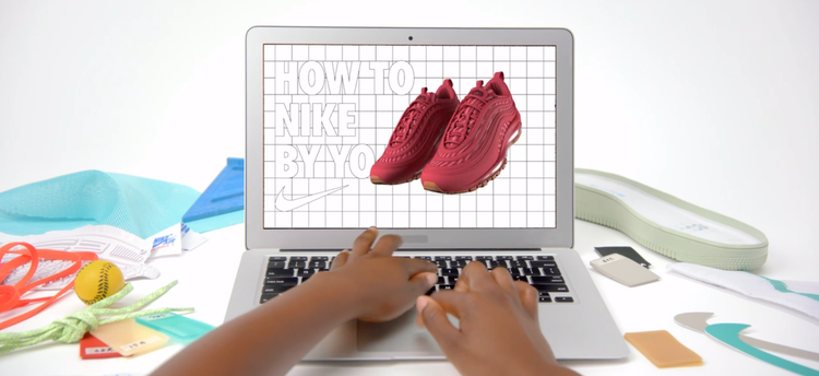 Hands typing on a laptop that shows personalized red Nike shoes on the screen.