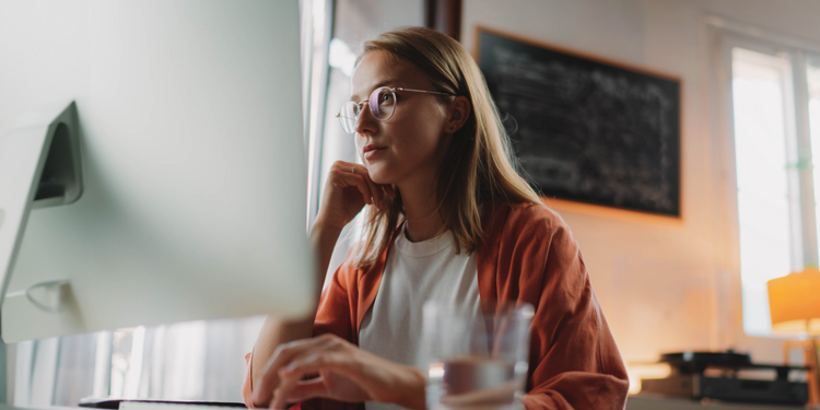 A marquee image of a woman in her home looking at a computer monitor.