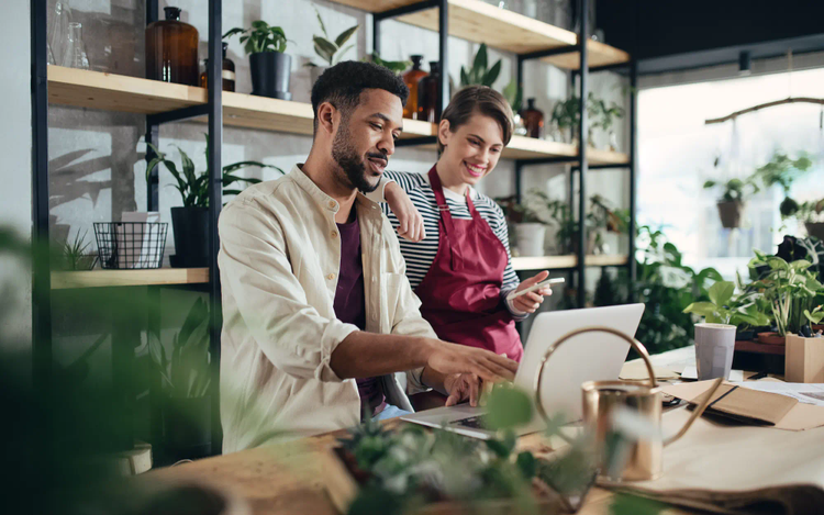 Man and woman in working on a laptop surrounded by plants