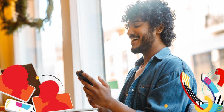 Smiling man using phone in front of laptop