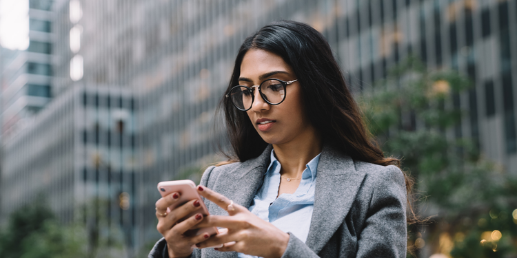 A woman executive uses her phone to improve her customer's experience by using website personalization.