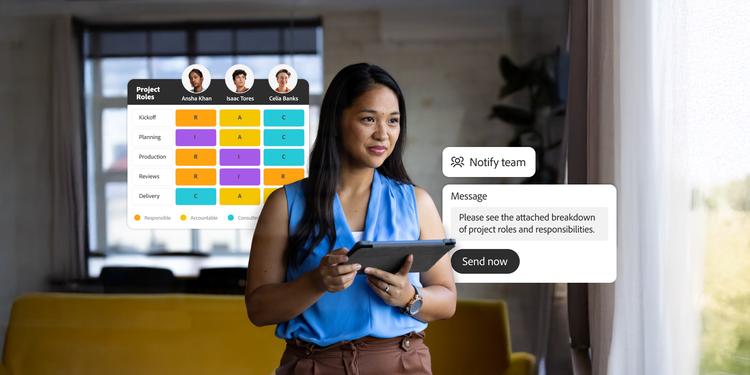 Woman holding a tablet stands in a modern room. Behind her is a project roles chart and a message draft to notify the team about roles and responsibilities.