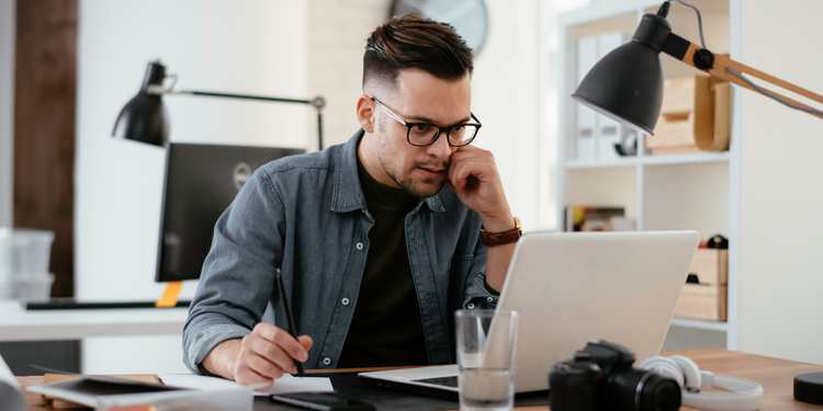 A project manager in an office oversees tasks using a laptop.