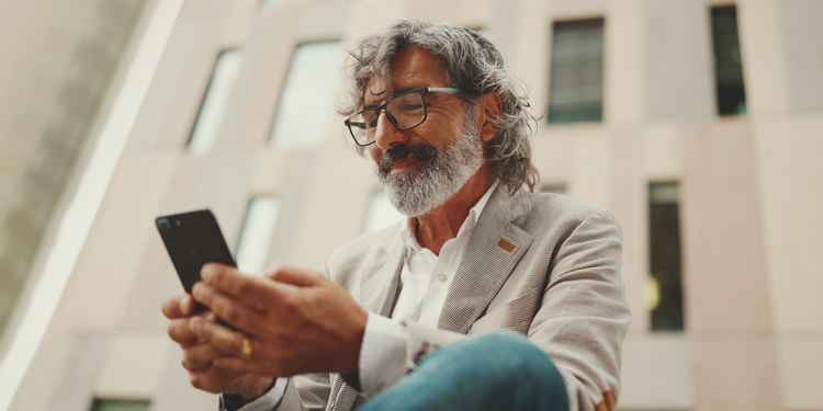 A man sitting outside a building uses a mobile phone to develop an ecommerce conversion funnel to drive business growth.