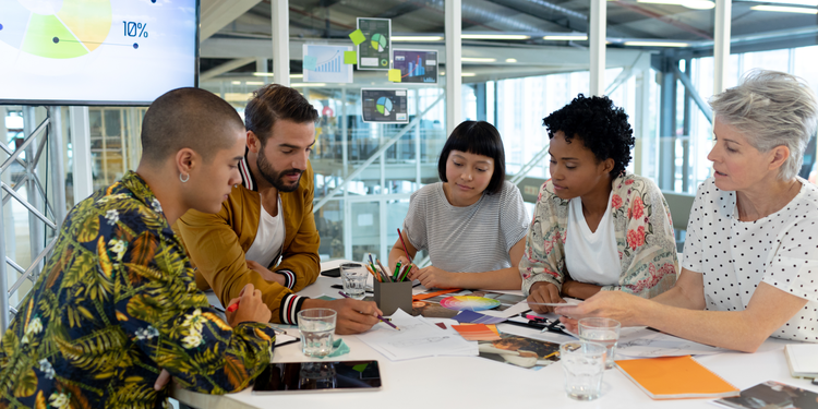 A group of colleagues at a desk discussing and deciding work projects.