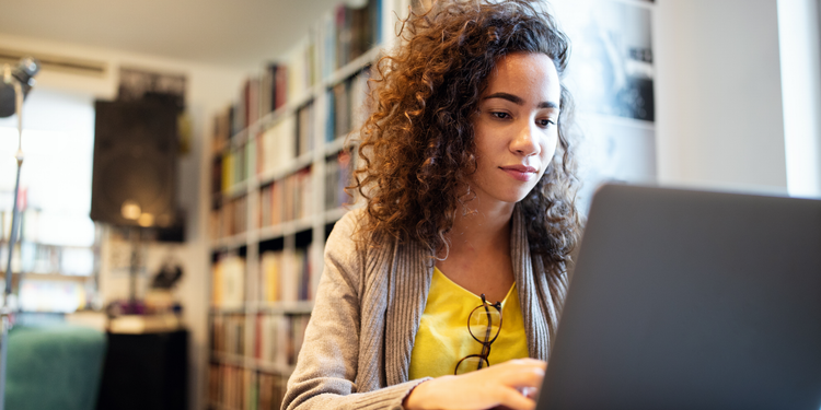 A female business professional calculates customer acquisition cost on a laptop.