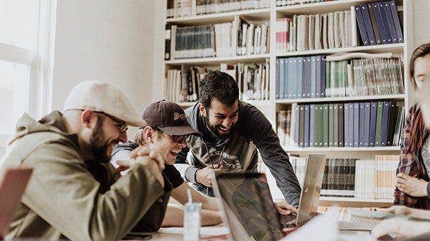 An agile team in a room laughing at a laptop