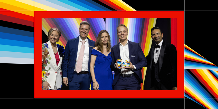 Telmore representatives accepting an award at the 2025 Experience Maker Awards gala, in front of a rainbow-striped background.