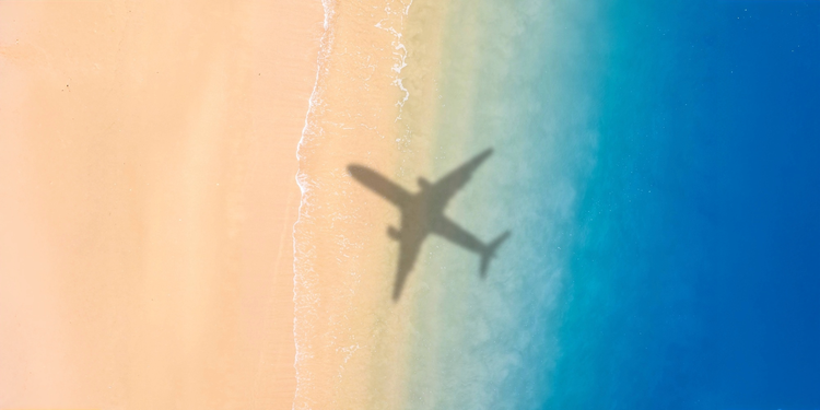 Airplane shadow over beach and ocean shoreline