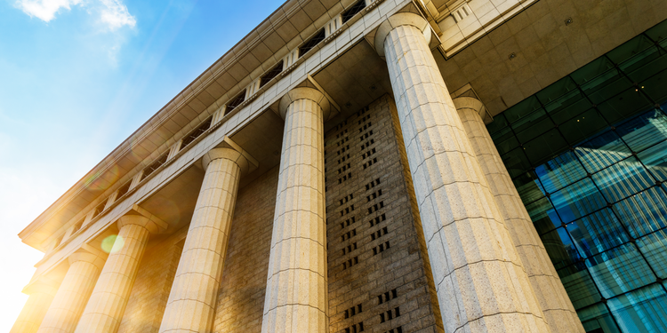 Looking upward at a neoclassical style government building, focusing on six columns.