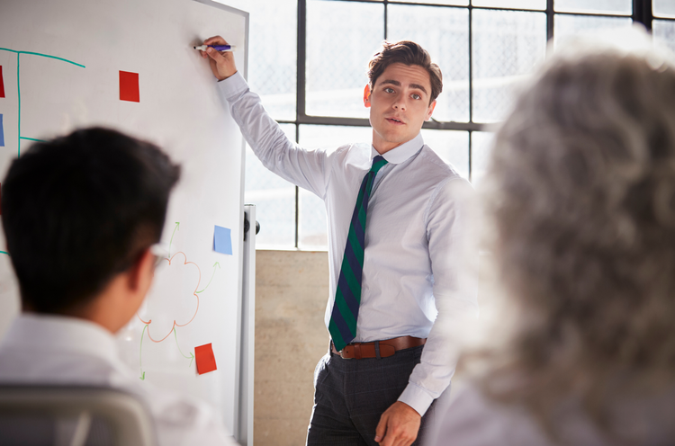 Man writing on a whiteboard in an office setting