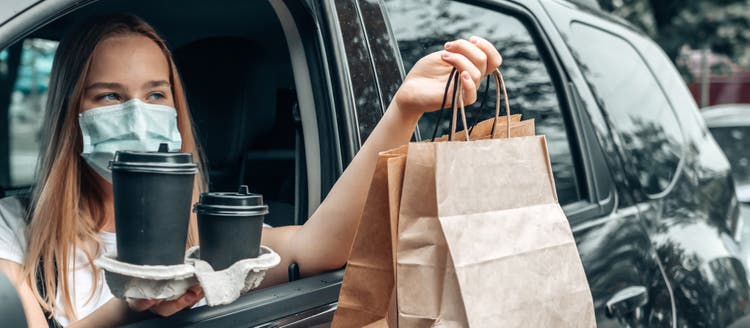 Women in car with mask on receving food order