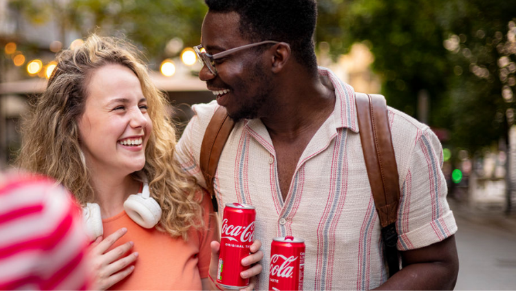 Un homme et une femme souriant avec une canette de Coca-Cola à la main