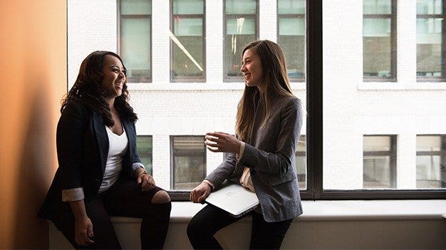 A scrum product owner talking to a scrum team member by a window