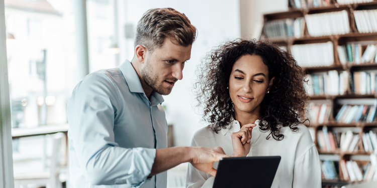 Two business professionals looking at an iPad screen discuss the benefits of social media marketing.