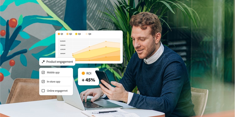 テーブルでノートパソコンを使いながらスマートフォンを見ている男性。