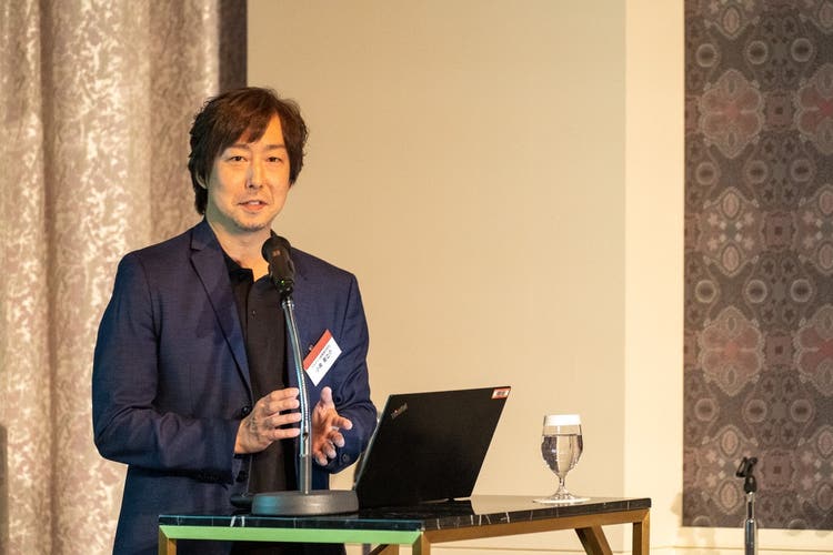 ノートパソコンの前に立っている男性 低い精度で自動的に生成された説明