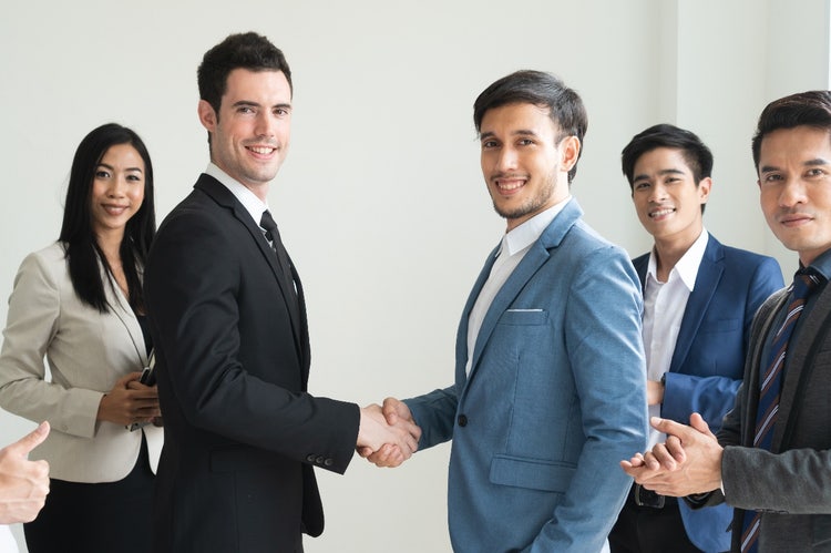 men shaking hands in a group of people