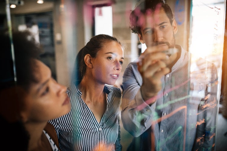 People looking at chart on a glass whiteboard