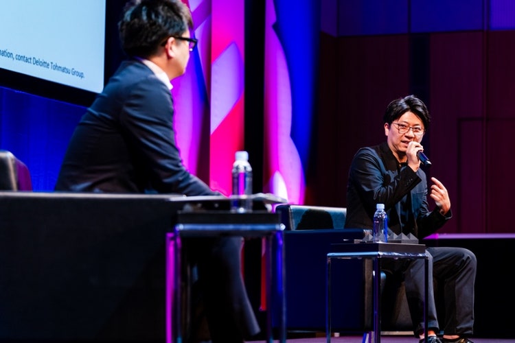 ステージでギターを弾いている男性 自動的に生成された説明