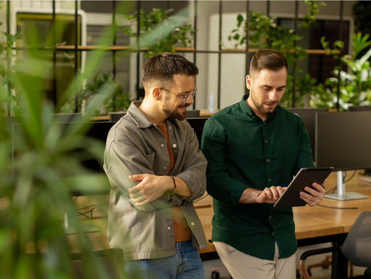 Two men in an office reviewing documents on a tablet