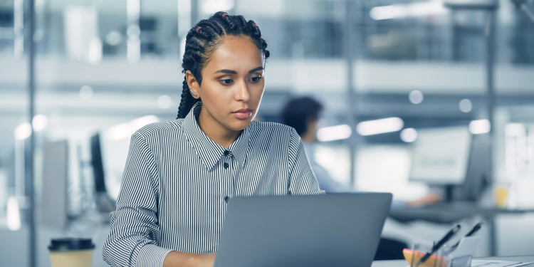 A female business professional types on a laptop.