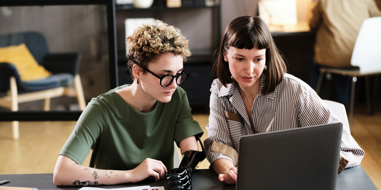 A project manager and a scrum team member use a laptop to develop agile work goals during a sprint.