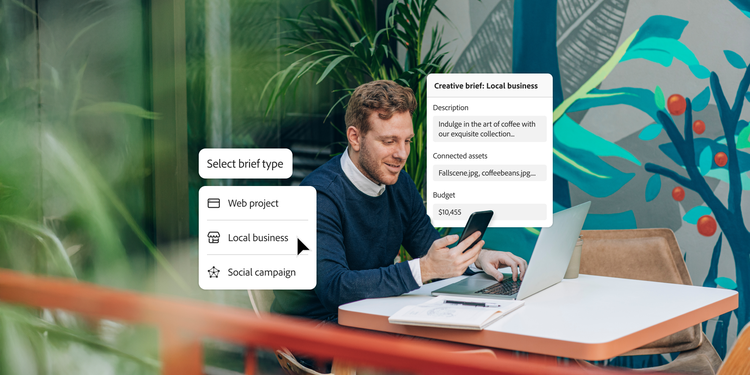 A smiling man seated at a table in a modern, vibrant workspace is using a smartphone and laptop simultaneously. Floating interface elements beside him show options for selecting a project type (